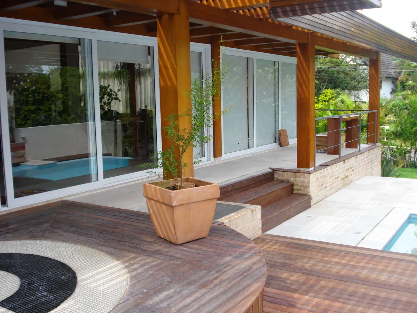 Deck de madeira de uma residência integrado à piscina e ao jardim