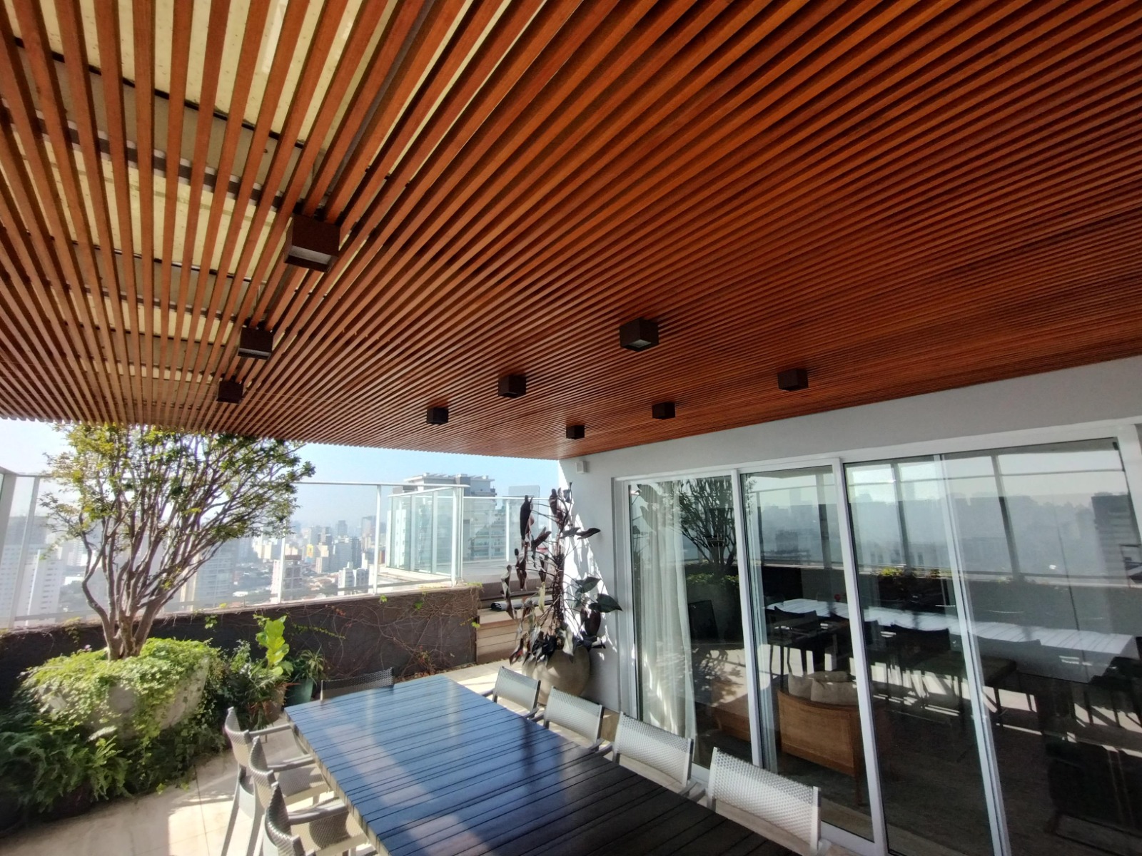 Varanda com forro de madeira, mesa e vista para a cidade
